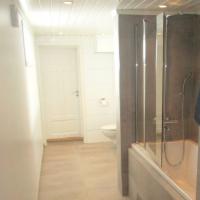 Ferdig baderom med badekar, dusjvegger, vegghengt WC, vask og speil. Fliser på gulv og enkelte vegger. Våtromsplater på andre vegger.