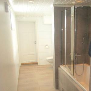 Ferdig baderom med badekar, dusjvegger, vegghengt WC, vask og speil. Fliser på gulv og enkelte vegger. Våtromsplater på andre vegger.