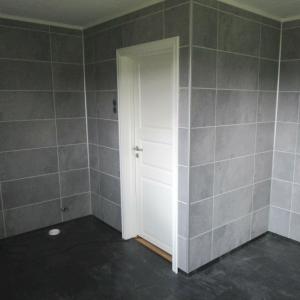 Ferdig listet rundt dør med hvitmat listverk. Rør til WC stikker ut av gulv og vegg.